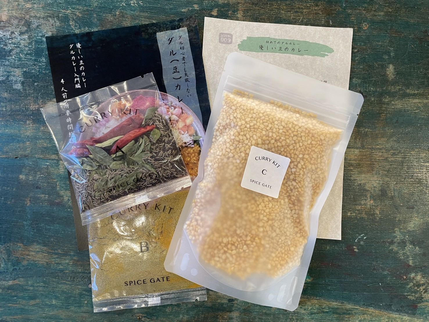 『優しい豆のカレー』キットの中身。スパイス2袋とイエロームングダルの大袋、店頭の紹介カードとレシピ用紙